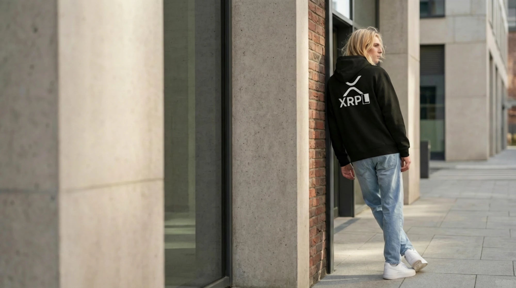 Person wearing a black XRP hoodie with a logo, standing in an urban setting.